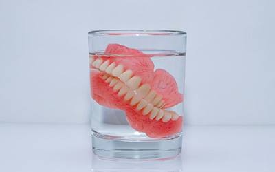 Dentures soak in glass of clear fluid