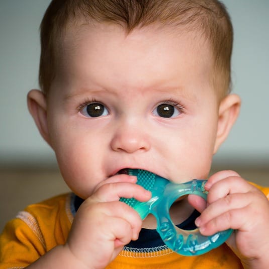 baby chewing on teething toy