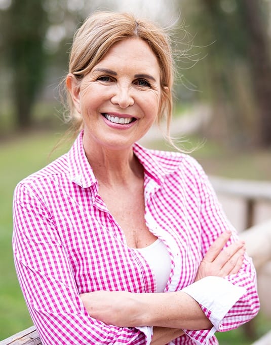 woman with plaid shirt smiling outside