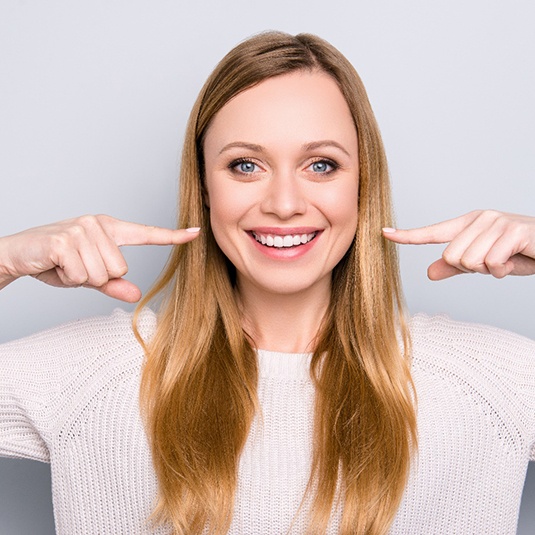 Young woman pointing to a healthy smile. 