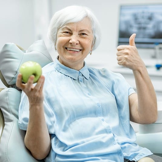woman holding apple and doing thumbs up