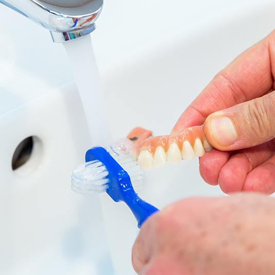 man brushing his dentures