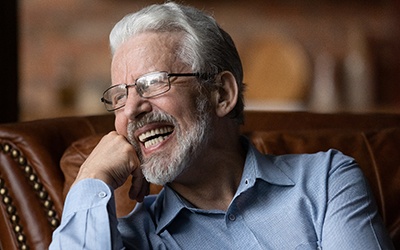 Man with dentures laughing on a couch