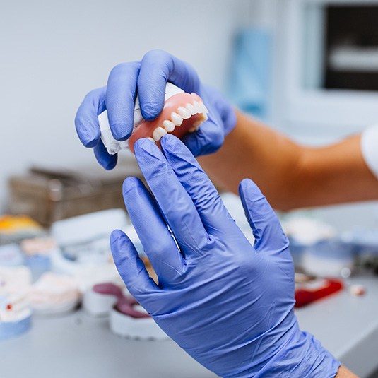 Gloved hands holding a denture