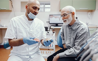 A dentist showing dentures to an older man