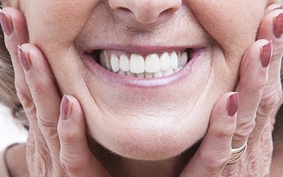 close-up of a smiling woman holding her cheeks 