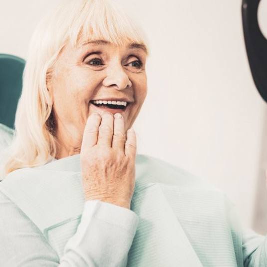 dental implant patient admiring her new smile in the mirror 