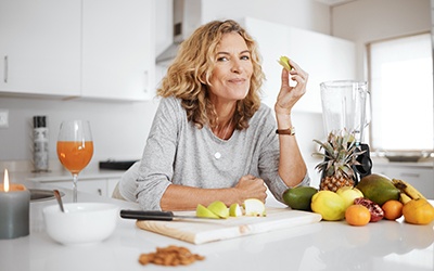 Smiling woman snacking on fruit in kitchen
