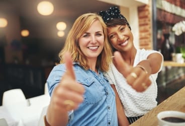 two woman doing thumbs up
