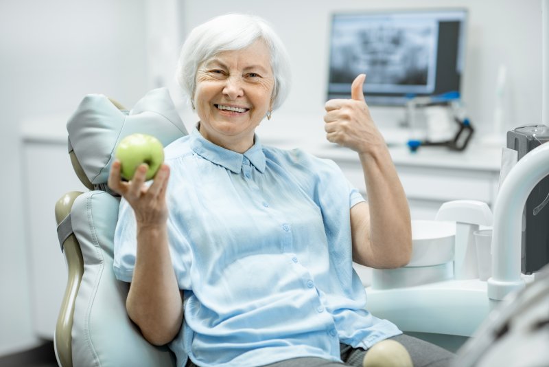 Woman smiling and holding a green apple