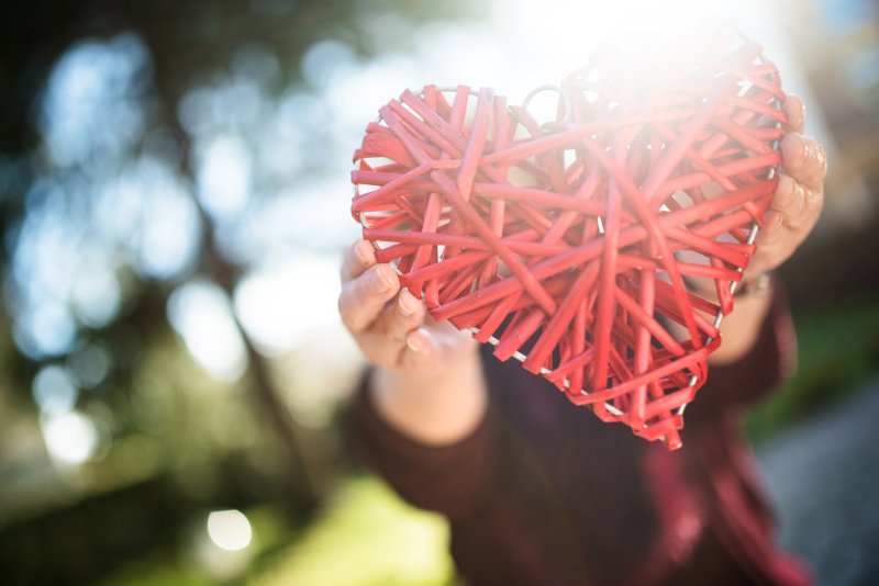 A woman holding a threaded heart for Heart Health Month.