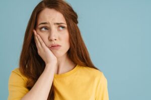 Young woman holding face in pain.